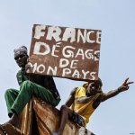 Fuentes: El Diario [Foto: Dos manifestantes con un cartel que dice «Francia, lárgate de mi país»]