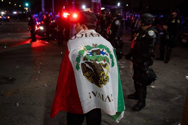 Un manifestante envuelto en una bandera mexicana durante una protesta tras las operaciones federales de inmigración, en el barrio de Compton, Los Ángeles, California, la madrugada del 8 de junio de 2025. Foto Afp
