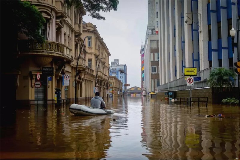 Un hombre recorre con un bote inflable las calles inundadas por fuertes lluvias en Porto Alegre, sur de Brasil, mientras que en el norte del país los ríos se reducían a mínimos históricos debido a una sequía sin precedentes. En todo el mundo los ciclos del agua tienen cada vez más comportamientos extremos, en perjuicio de la vida y la economía de las sociedades. Imagen: Dialogue Earth.