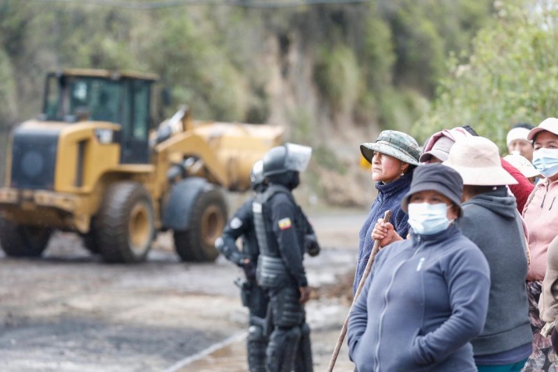 Mujeres indígenas observan a los elementos de la policía abrir la circulación en la vía Tabacundo-Cajas, en la comuindad de Pichincha, luego que se anunció el fin de las movilizaciones de la Confederación de Nacionalidades Indígenas de Ecuador (Conaie), el 22 de octubre de 2025. Foto Xinhua