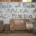 Un voluntario realiza un graffiti en un mural del barrio de El Raval en el que se lee: 'Solo el pueblo salva al pueblo', en Algemesí, València. | Alejandro Martínez Vélez / Europa Press / ContactoPhoto