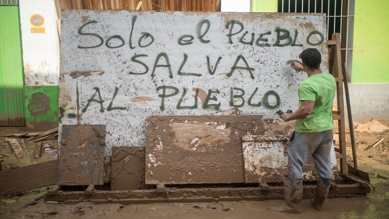Un voluntario realiza un graffiti en un mural del barrio de El Raval en el que se lee: 'Solo el pueblo salva al pueblo', en Algemesí, València. | Alejandro Martínez Vélez / Europa Press / ContactoPhoto