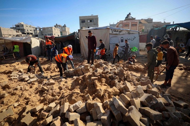Trabajadores del municipio palestino reparan una carretera dañada durante la guerra en el campamento de desplazados de Nuseirat, en el centro de la Franja de Gaza, el 22 de diciembre de 2025. Foto Afp