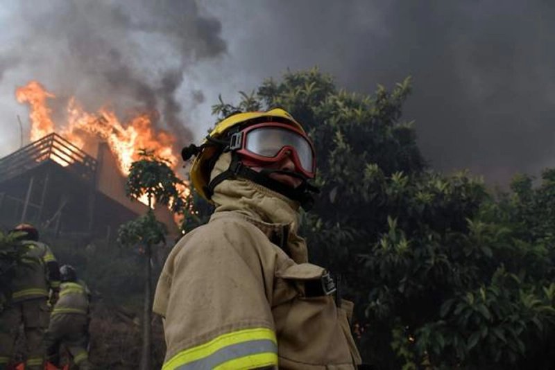 Bomberos intentan extinguir una casa en llamas durante un incendio forestal en Concepción, Chile, el pasado 18 de enero de 2026. Foto Afp