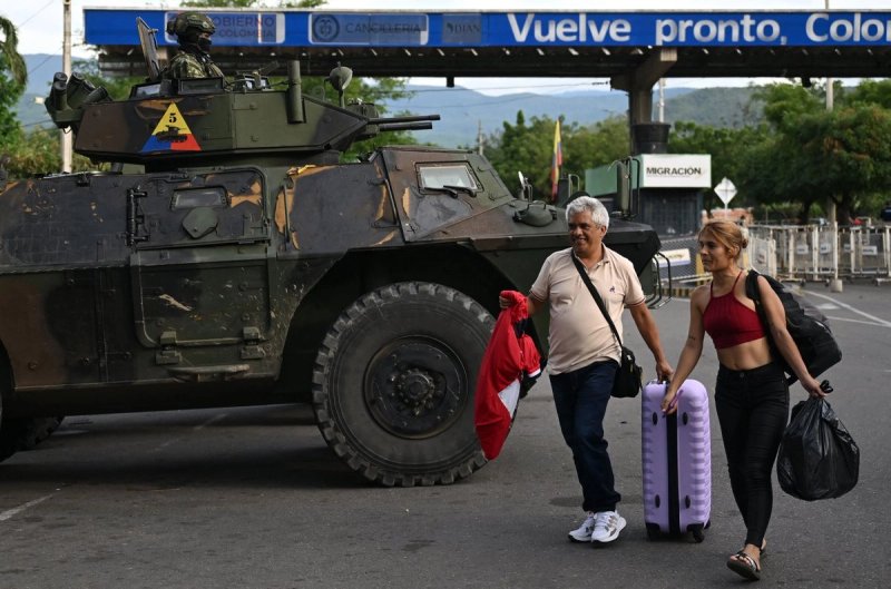 Dos mujeres pasan junto a un vehículo militar en el cruce fronterizo con Venezuela en Cúcuta, Colombia, el 3 de enero de 2026, después de que las fuerzas estadunidenses capturaran al presidente venezolano, Nicolás Maduro. Foto Afp