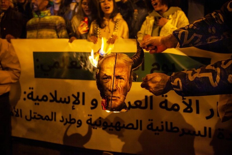 Un manifestante quema una imagen compuesta del presidente estadunidense Donald Trump y el primer ministro israelí Benjamin Netanyahu durante una manifestación con motivo del Día Internacional de Al-Quds en Túnez, Túnez, el viernes 13 de marzo de 2026. El lema reza: "Fin a la ocupación". Foto: Ap