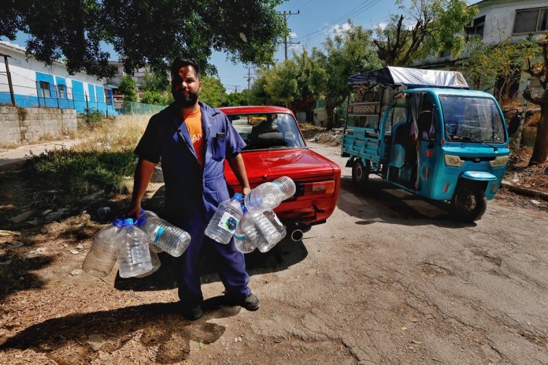 Un hombre carga botes para recibir agua potable en la zona de la 5ta avenida en la Habana, Cuba. Foto: Marco Peláez