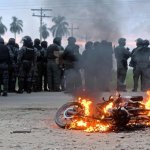 Una motocicleta arde cerca de agentes de policía durante enfrentamientos con manifestantes antigubernamentales en el marco de una operación para despejar un bloqueo vial en San Julián, departamento de Santa Cruz, Bolivia, el 6 de junio de 2026. Foto: Afp
