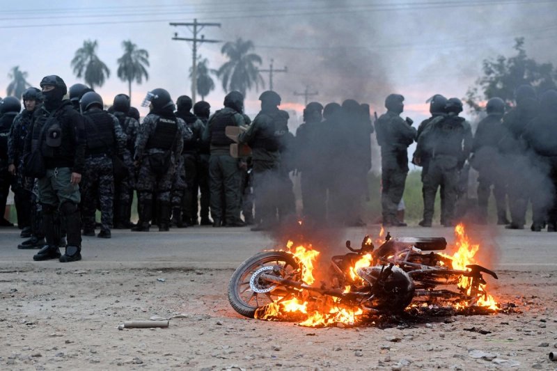 Una motocicleta arde cerca de agentes de policía durante enfrentamientos con manifestantes antigubernamentales en el marco de una operación para despejar un bloqueo vial en San Julián, departamento de Santa Cruz, Bolivia, el 6 de junio de 2026. Foto: Afp